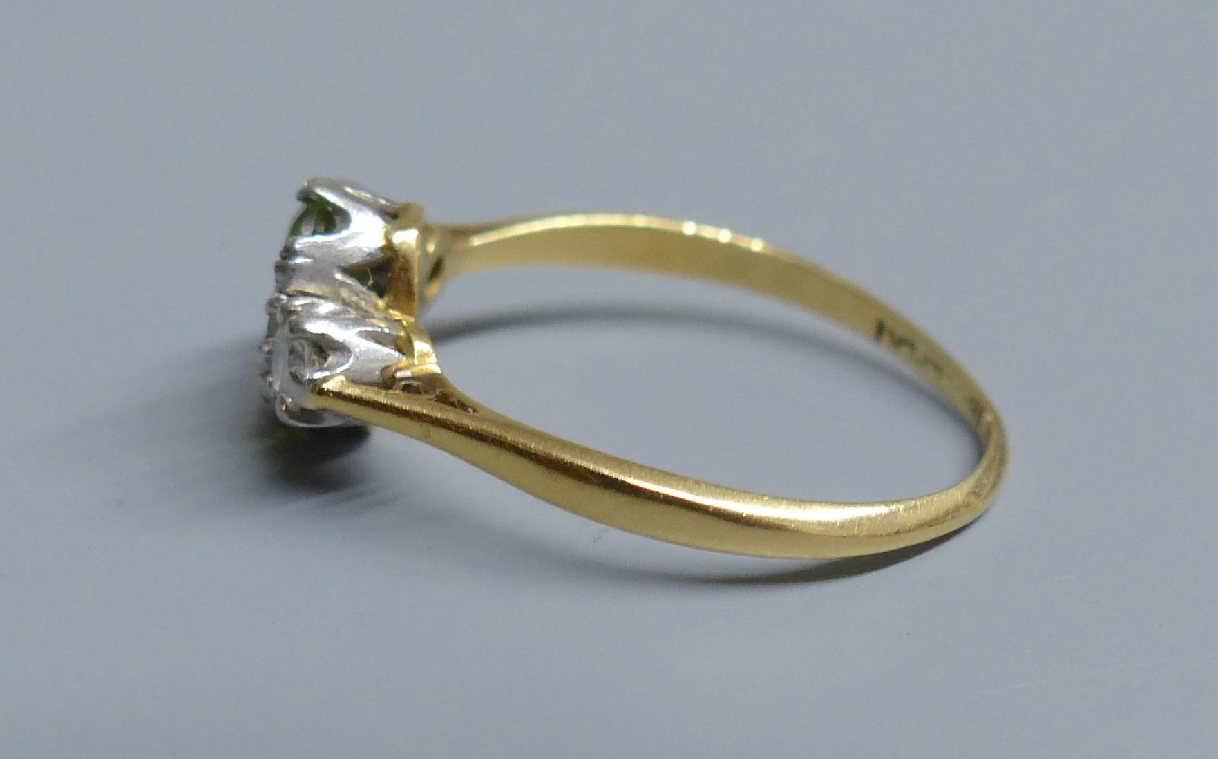 An 18ct and plat. peridot and diamond set three stone ring, size N, gross 2.5 grams.